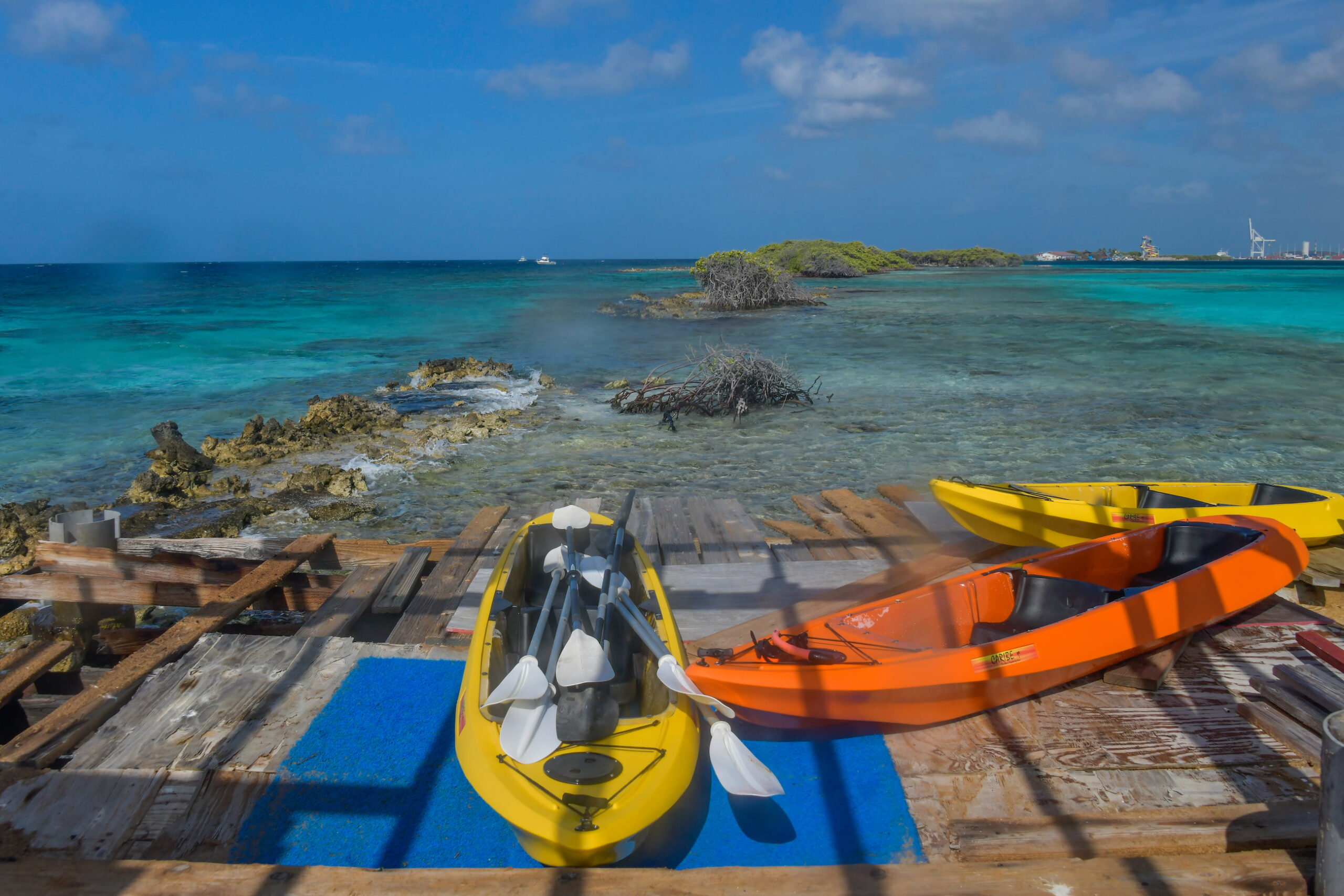 Kayaks docked on a wooden platform overlooking a reef, marking a snorkeling stop during the Mangel Halto tour.