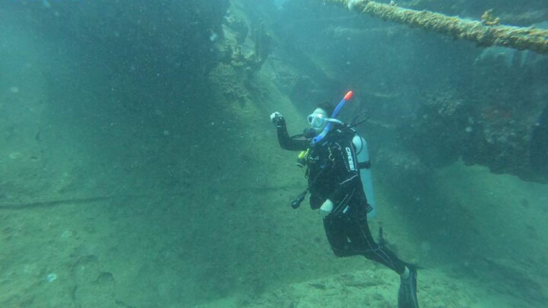 Scuba diver swimming through wreck interior passage underwater